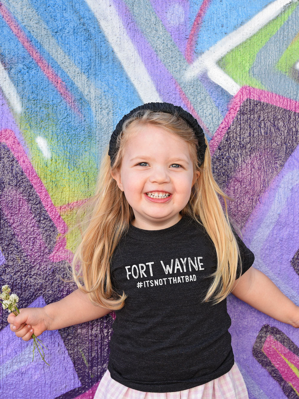 Fort Wayne #itsnotthatbad black heather kids t-shirt on model by purple mural