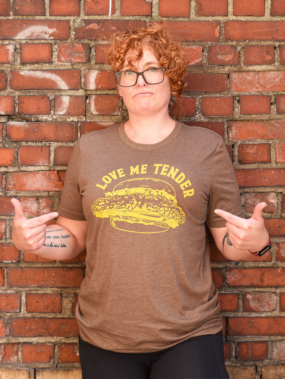 Love Me Tender (pork tenderloin sandwich) brown heather t-shirt on model in front of brick wall