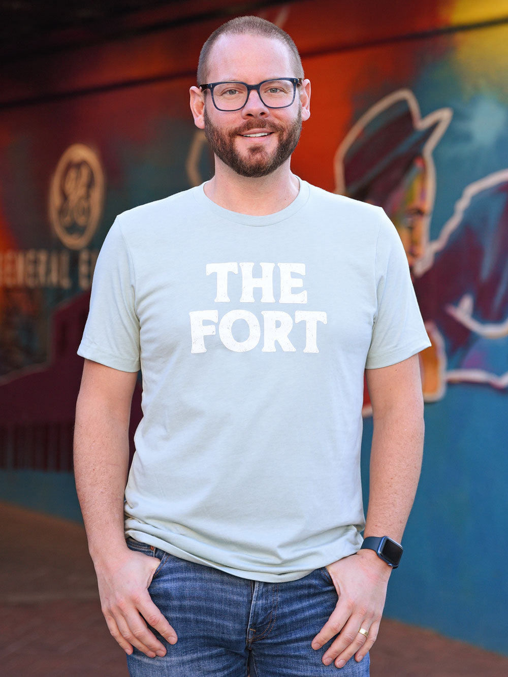The Fort dusty blue heather t-shirt on model in front of mural