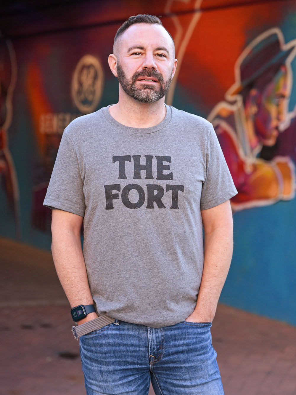 The Fort gray heather t-shirt on model in front of mural